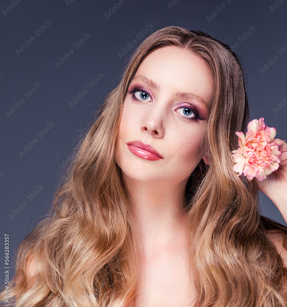 A beautiful young woman with shiny wavy brown hair. Model with healthy skin, close up portrait. Girl with a carnation flower A beautiful young woman with shiny wavy brown hair. Model with healthy skin, close up portrait. Girl with a carnation flower