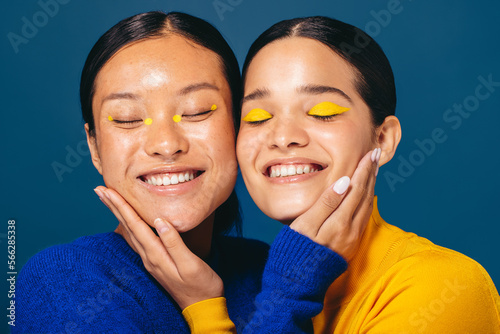 Best friends in beauty: Two young women smile and embrace each other with makeup on photo