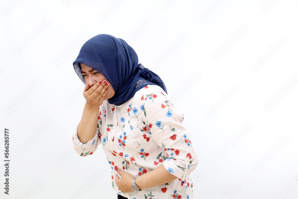 Asian muslim woman standing while holding her stomach and feeling nauseous and going to vomit Asian muslim woman standing while holding her stomach and feeling nauseous and going to vomit