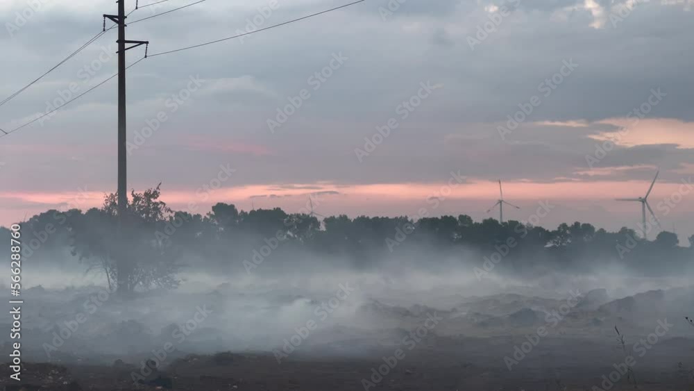 Smoke comes out from burned landfill site during sunset Smoke comes out from burned landfill site during sunset