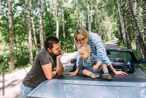 Mom, dad and little son in a convertible car. Summer family road trip to nature