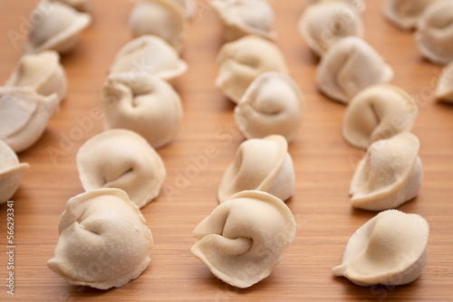 Frozen uncooked dumplings pelmeni on a wooden board