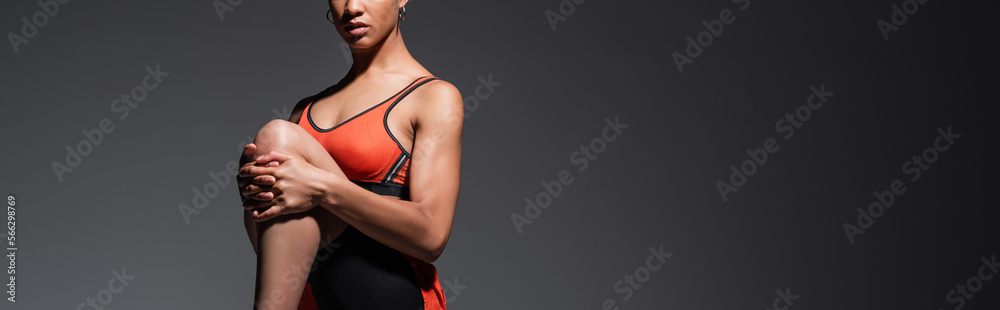 cropped view of young african american sportswoman in sportswear exercising on grey, banner.