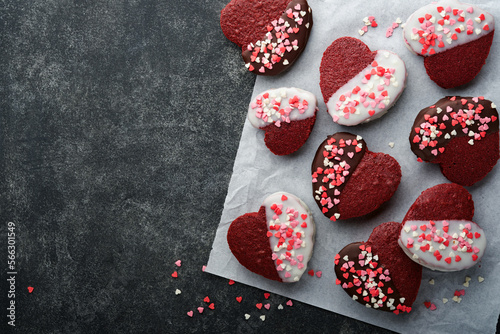 Red velvet or brownie cookies on heart shaped in chocolate icing with red roses on black background. Dessert idea for Valentines Day, Mothers or Womens Day. Homemade dessert. Cake for Valentines Day.