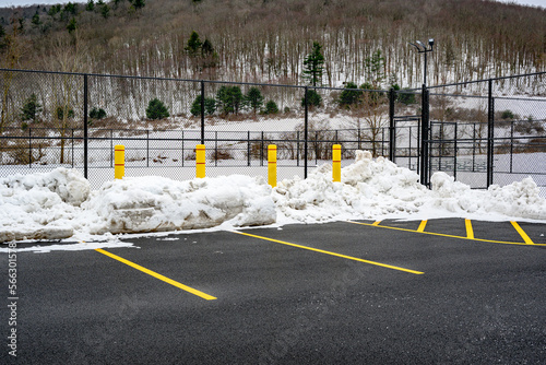 4 Large Yellow Concrete Pillars are placed on the edge of the parking lot to protect the Tennis Court fences from being damaged during snow plowing in the winter in Upstate NY.