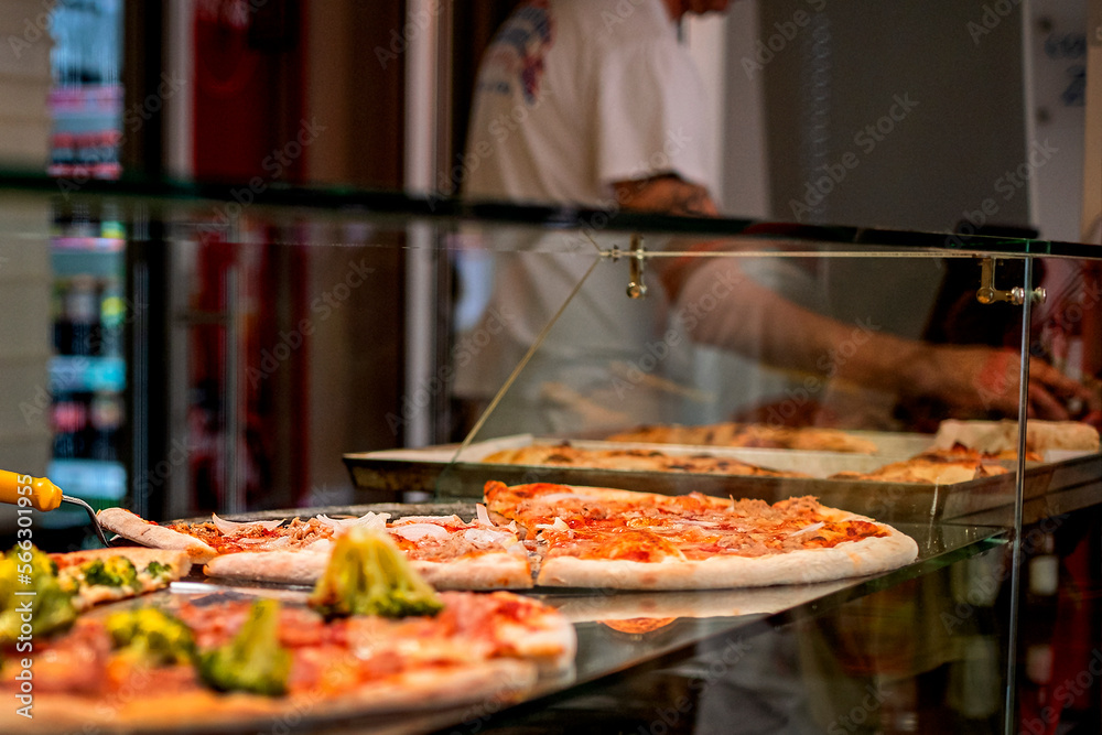 Large pizza cut into slices on the counter, italian street style