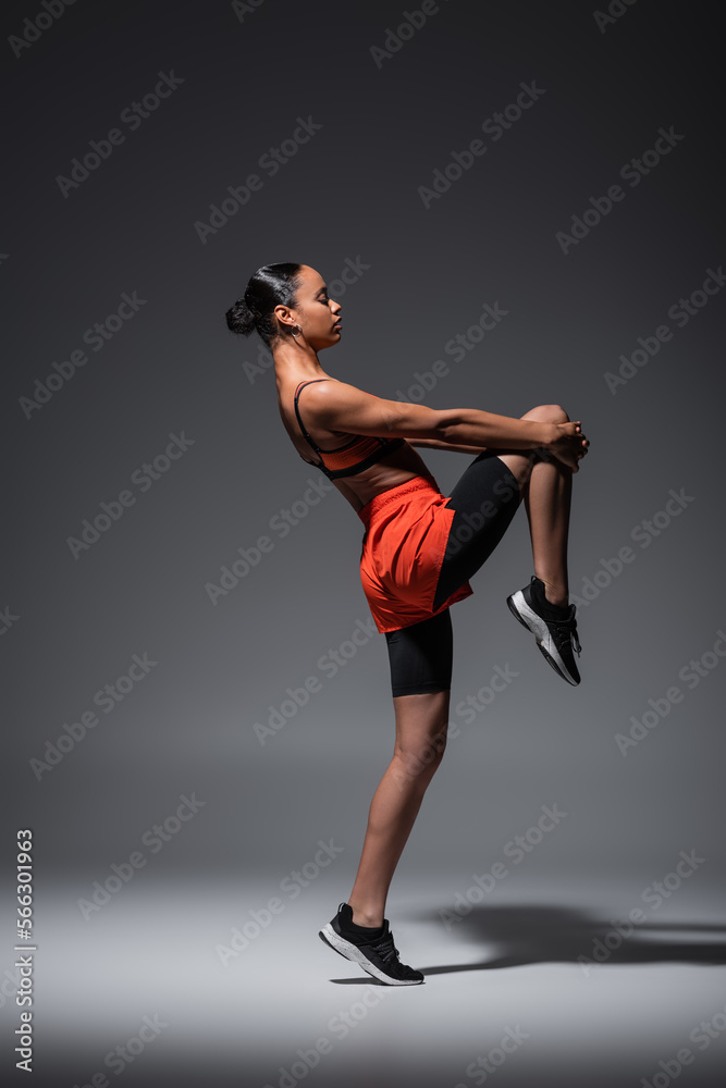 full length of sportive african american woman in sneakers training on grey.