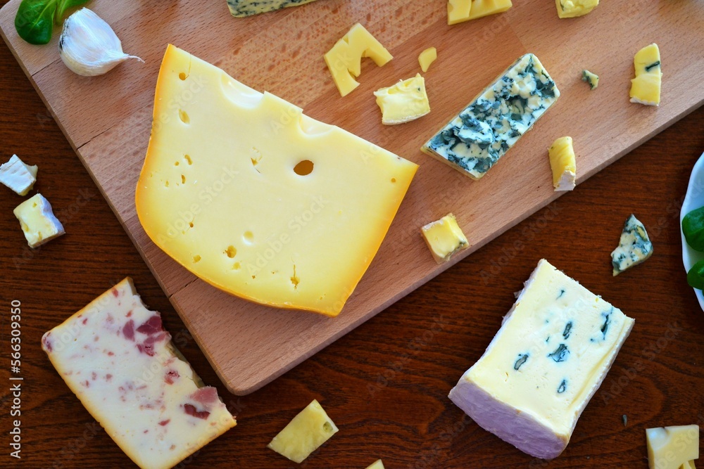 Assortment of cheeses on a cutting board and a wooden table