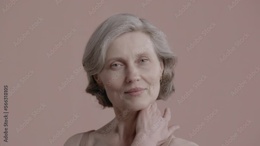 Portrait of beautiful 60s grey-haired mature senior adult female posing without makeup against light brown background. Studio shot, soft lighting. No make up, clean skin. Shot with ARRI Alexa Mini LF Portrait of beautiful 60s grey-haired mature senior adult female posing without makeup against light brown background. Studio shot, soft lighting. No make up, clean skin. Shot with ARRI Alexa Mini LF