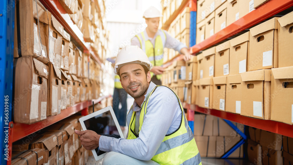 A worker in the warehouse uses a smart tablet to check the stock is on the shelves at the manufacturing. A worker in the warehouse uses a smart tablet to check the stock is on the shelves at the manufacturing.