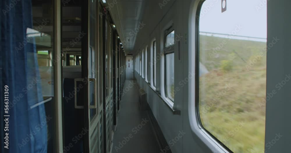 Empty car of an intercity train in motion on a sunny day. Traveling by train through the countryside, the view from the window, empty seats inside the car. Empty seats on train traveling across Europe