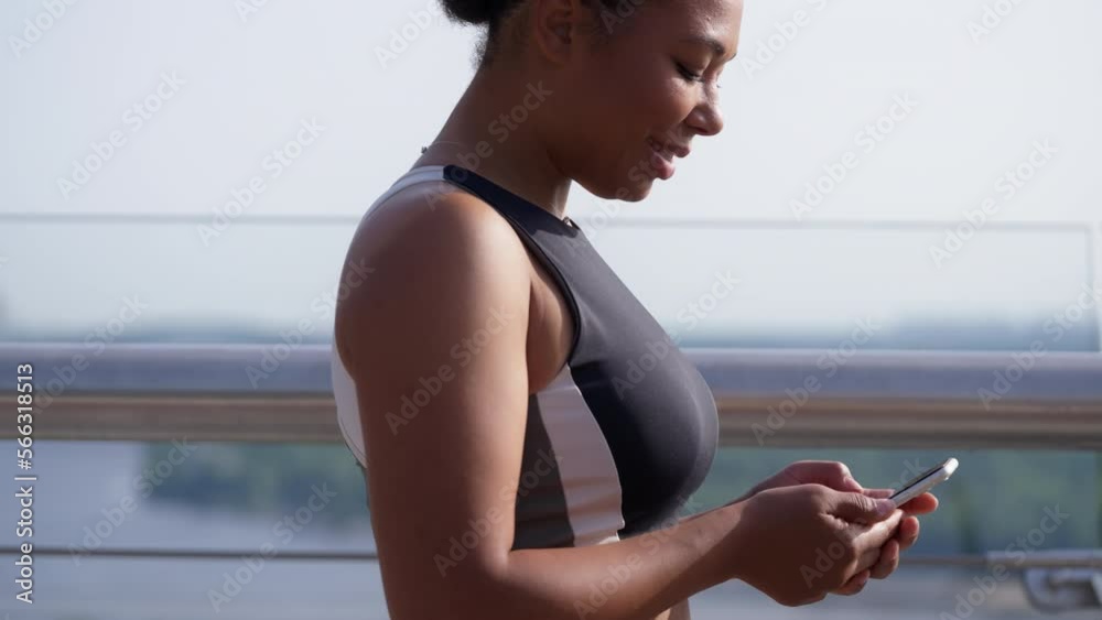 African American female athlete texting on smartphone during jogging, sports app