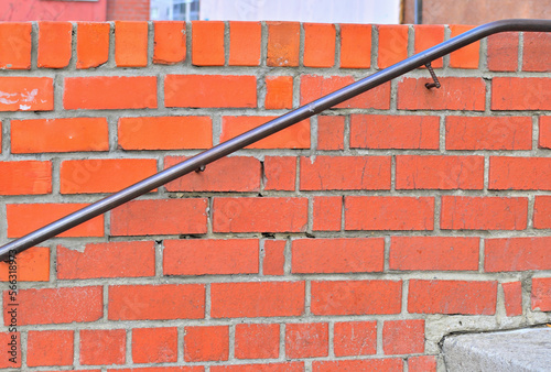 Metal railing at the brick wall close-up