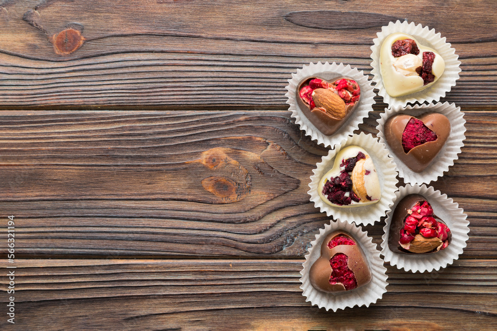 chocolate sweets in the form of a heart with fruits and nuts on a colored background. top view with space for text, holiday concept chocolate sweets in the form of a heart with fruits and nuts on a colored background. top view with space for text, holiday concept