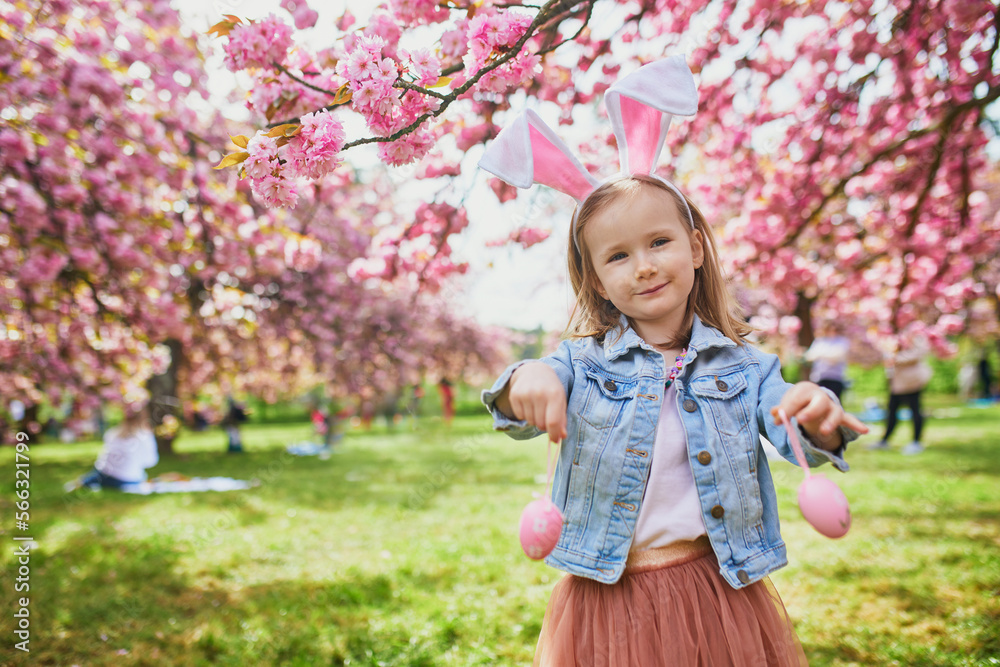 Preschooler girl wearing bunny ears playing egg hunt on Easter Preschooler girl wearing bunny ears playing egg hunt on Easter