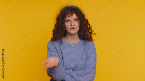 Quarrel. Displeased curly haired woman gesturing hands with irritation and displeasure, blaming scolding for failure, asking why this happened. Young teen girl isolated on yellow studio background © Andrii Iemelianenko