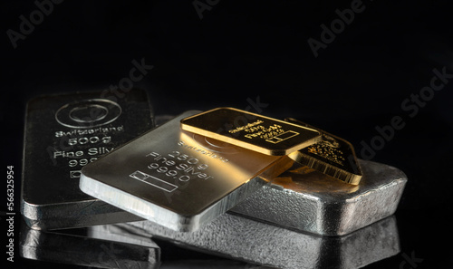 Gold and silver bars of various weights on a dark background. Selective focus.