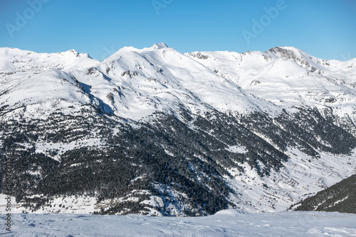Snowy landscape with trees and high mountains in the mountain range of the Pyrenees, Andorra. © josemiguelsangar