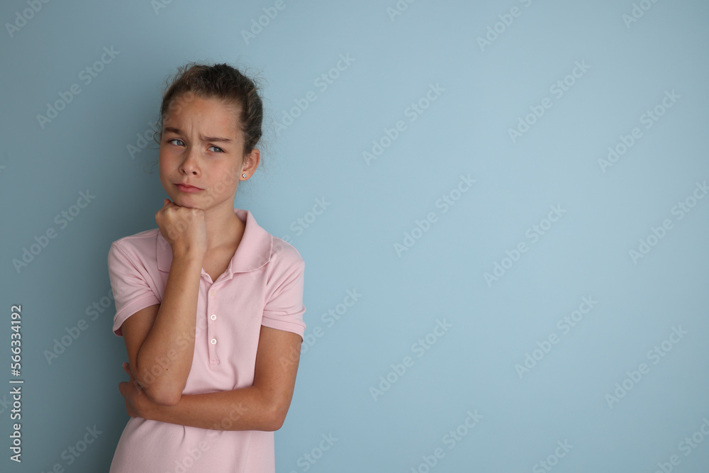 Little emotional teenage girl in pink shirt 11, 12 years old on an isolated blue background. Children's studio portrait. Place text to copy space for caption, advertising children's goods. Little emotional teenage girl in pink shirt 11, 12 years old on an isolated blue background. Children's studio portrait. Place text to copy space for caption, advertising children's goods.