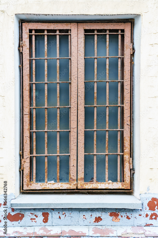 Old window with a metal grille of two sections