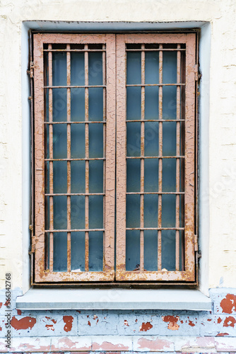 Old window with a metal grille of two sections