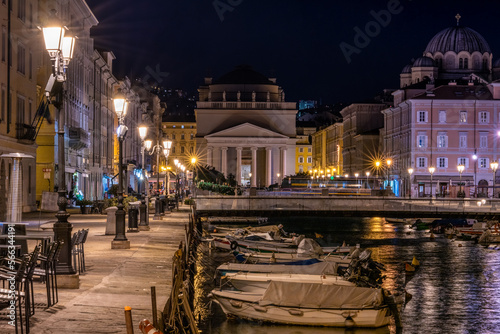 Piazza Sant'Antonio Nuovo in Trieste, Italy. Perspective along the canal with boats at night on the pier