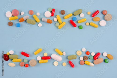 Tablets, capsules are multicolored on a blue background. Production and disposal of medicines.Pharmaceutical preparations.Sale of medicines.Vitamins for a healthy lifestyle.Copyspace.
