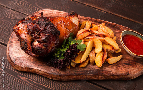 Pork knuckle, in soy-honey sauce, with fried potatoes, on a wooden chopping board, homemade, no people,