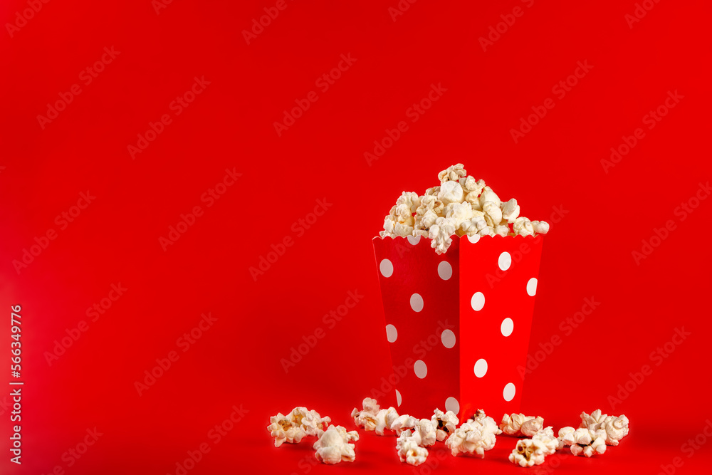 Popcorn in a red bag with white polka dots on a red background. Front view, copy space.