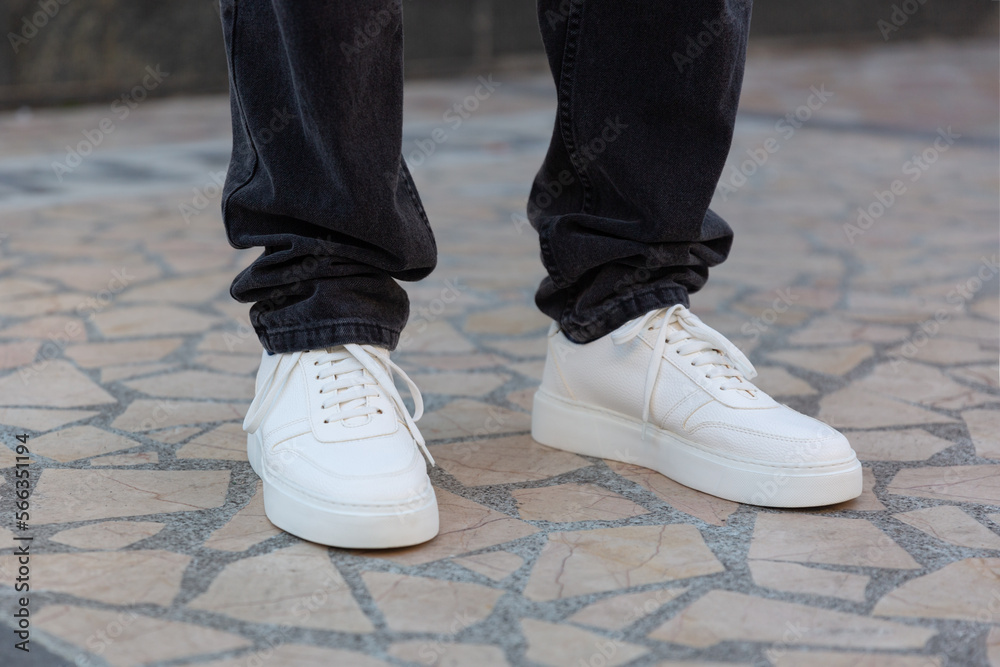 Stylish man in white sneakers shoes on city street
