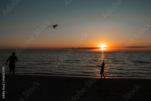 happy girl running with a kite at sunset outdoors. A child runs with a kite at sunset against the backdrop of the sea. Family vacation. High quality photo.