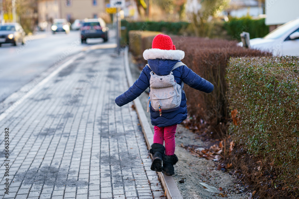 Cute little preschool girl with glasses on her the way to playschool. Healthy happy child walking to nursery school. Kindergarten kid with backpack going to day care on the city street, outdoors Cute little preschool girl with glasses on her the way to playschool. Healthy happy child walking to nursery school. Kindergarten kid with backpack going to day care on the city street, outdoors