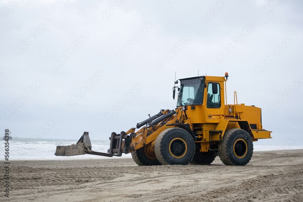 Yellow bulldozer excavating sand on dutch beach working. Clouded weather seashore netherlands. Heavy work equipment. Yellow bulldozer excavating sand on dutch beach working. Clouded weather seashore netherlands. Heavy work equipment.