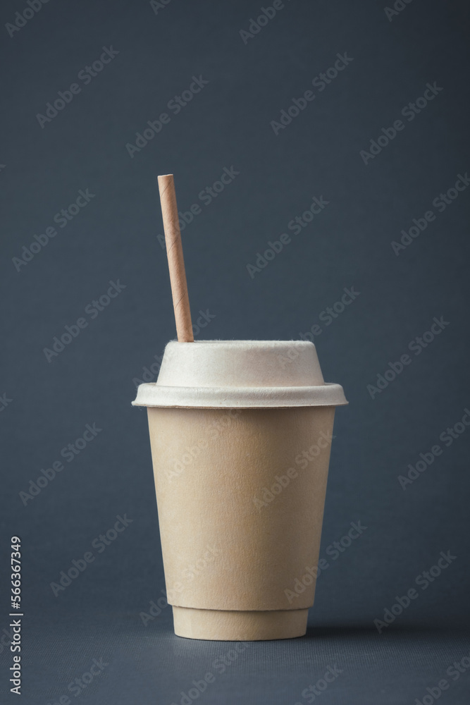 Coffee in a disposable paper cup with a straw on a gray background ...