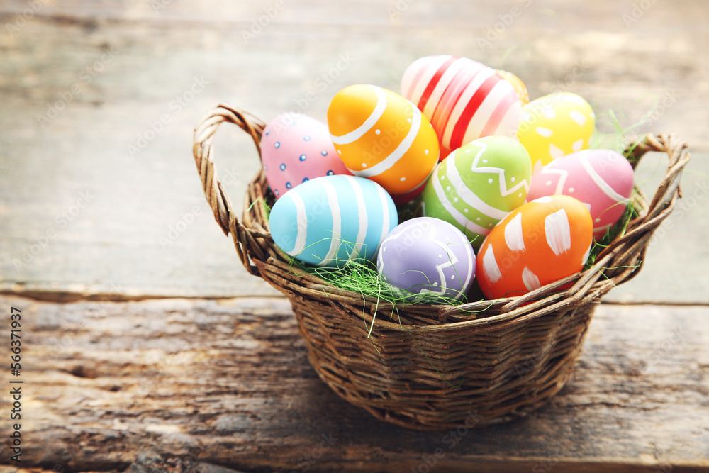 Colorful eggs in basket on wooden background. Easter day concept