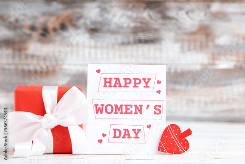 Card with text Happy Women's Day, gift and heart-shaped clothespin on wooden background