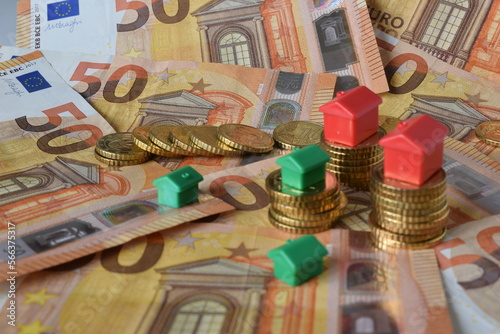 euro banknotes, coins and green and red houses