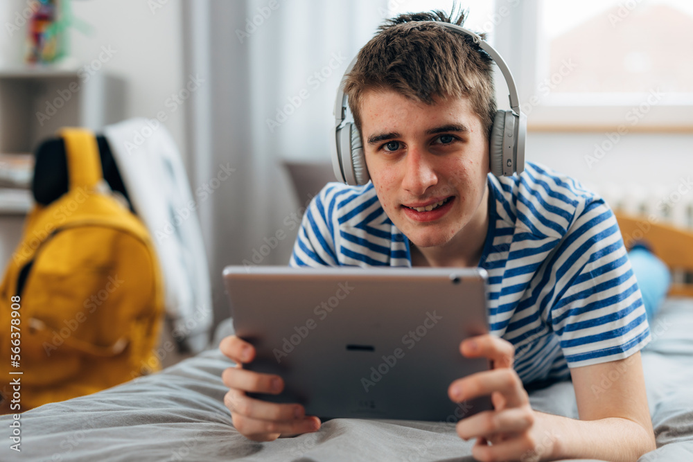A teenage boy is holding tablet and looking at the camera