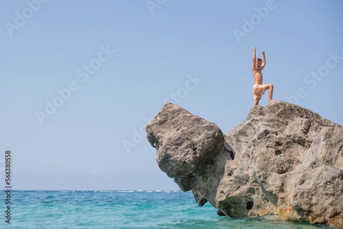 8-year-old happy boy in a victory pose stands on a rock. A dream holiday in Corfu, Greece