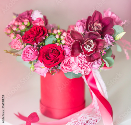 Rich bunch flowers in a red paper box on a light background. Bunch of red and pink fresh flowers