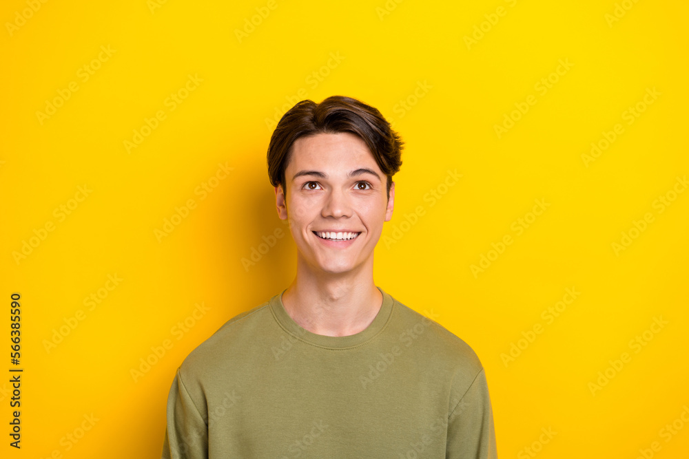 Photo of minded creative man beaming smile look interested up empty space isolated on yellow color background Photo of minded creative man beaming smile look interested up empty space isolated on yellow color background