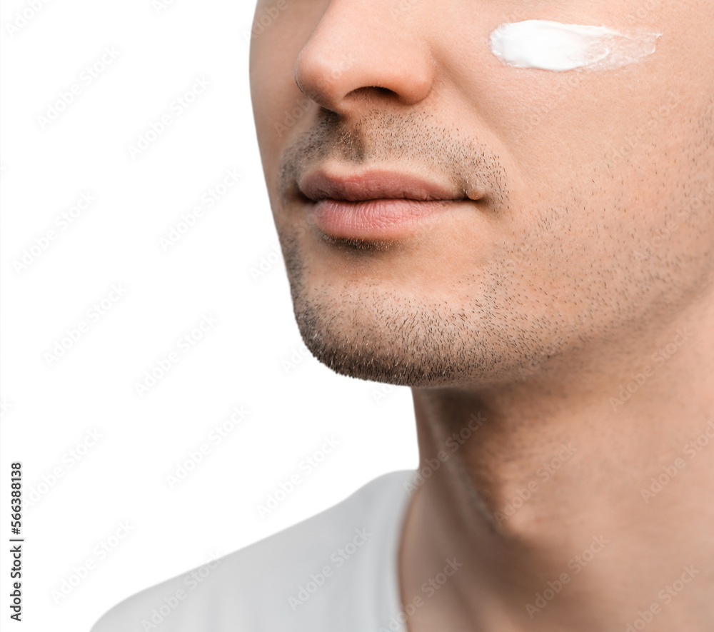 Fototapeta premium A portrait of a handsome man with a stubble in a white t-shirt, sample of a face cream on his cheek.