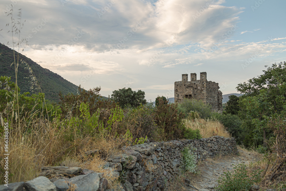 Panoramic view of the back of the tower of the San Sebastian church on the mountain. Selva de Mar, Girona, Spain. Romantic style. The path is made of stone and has walls on the sides.
