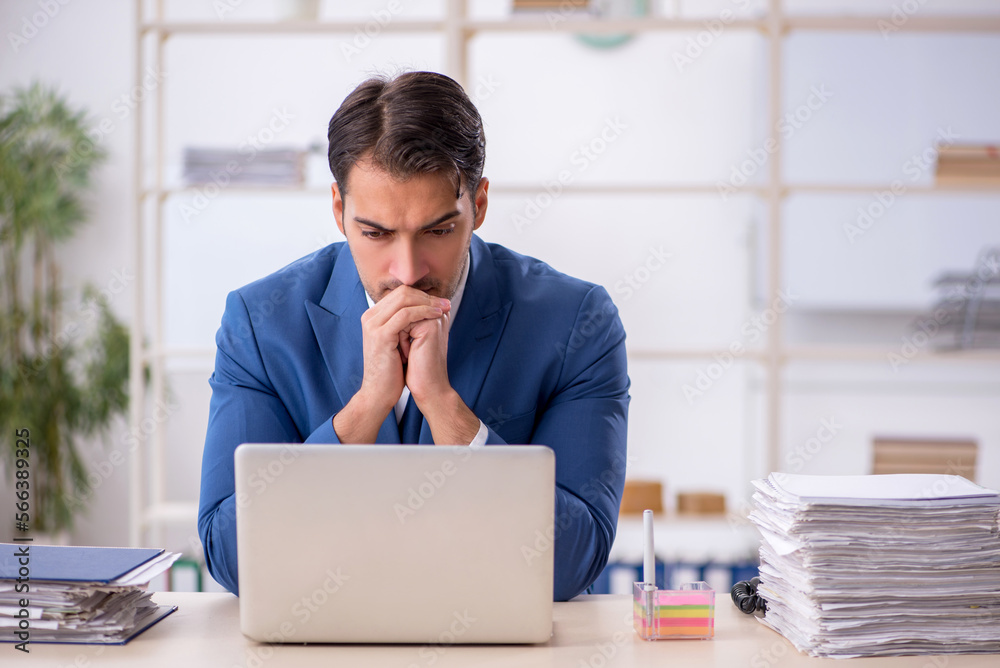 Young male employee and too much work in the office Young male employee and too much work in the office