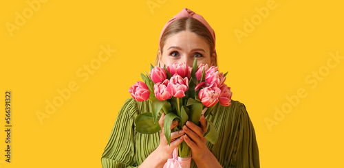 Beautiful woman with bouquet of tulips on yellow background. International Women's Day #566391322