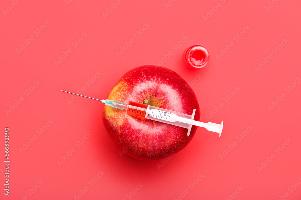 Medical syringe with remedy, ampule and apple on red background