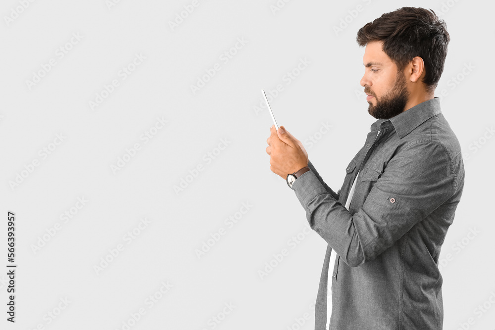 Handsome young businessman using tablet computer on light background Handsome young businessman using tablet computer on light background