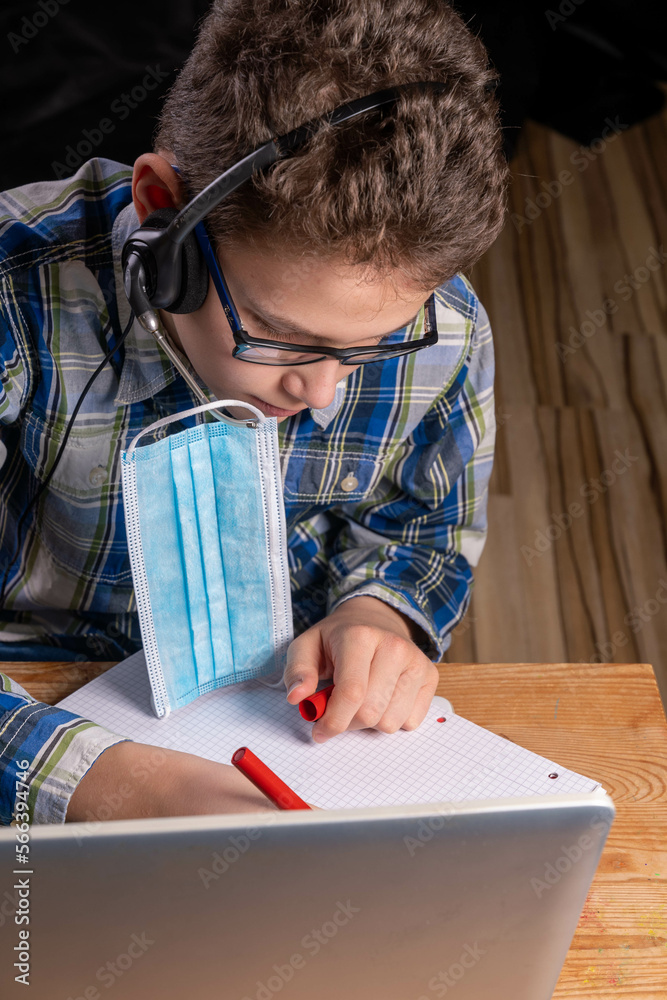 No more mask boy sitting at laptop with headset an red pen No more mask boy sitting at laptop with headset an red pen