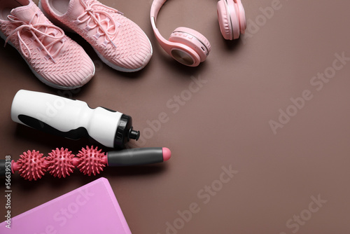 Sports water bottle with equipment, headphones and sneakers on brown background