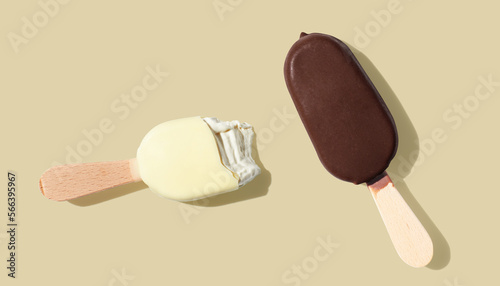 Chocolate and vanilla ice cream on a stick on yellow pastel background photo